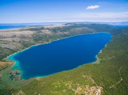 Una veduta del lago Vrana sull'isola di Cres, Croazia. Si trova a 700 metri di altitudine. Secondo antiche credenze, le grotte attorno a questo bacino sarebbero abitate da fate.

