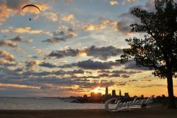 Veduta mattutina di Cleveland, Ohio, dal parco Edgewater: sullo sfondo, il lago Erie, la skyline della città e una persona con parapendio.
