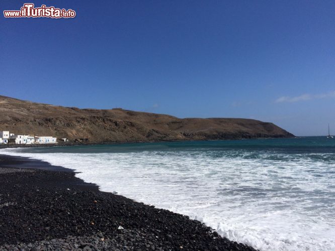 Immagine Fotografia della costa di Pozo Negro, Fuerteventura, Spagna - A differenza delle altre spiagge presenti nelle Canarie che si sviluppano per chilometri di sabbia bianca continua, qui la differenza è netta. Pochissima estensione (non raggiunge 1km), ghiaia e sassi neri, un silenzio e una tranquillità senza pari, ridotte abitazioni. Il luogo ideale per chi ama distinguersi, desidera tranquillità e apprezza le tradizioni locali. Questo luogo infatti rappresenta il cuore più a sud di Caleta de Fuste e prende il nome dal villaggio di pescatori.