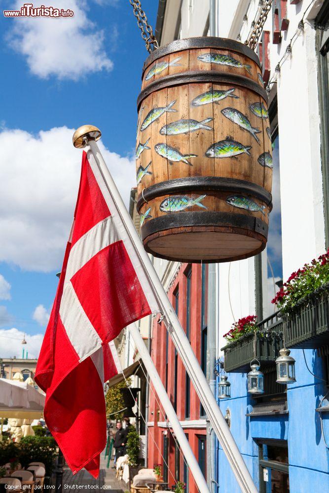 Immagine La bandiera danese e un grande barile di legno decorato con pesci a Copenaghen, Danimarca. Le specialità a base di pesce si possono assaporare nei tradizionali ristoranti della città - © jorisvo / Shutterstock.com