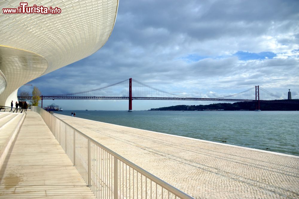 Immagine Le forme sinuose del MAAT (Museo di Arte, Architettura e Tecnologia) di Lisbona e, in lontananza, il Ponte 25 de Abril, simbolo della capitale portoghese.