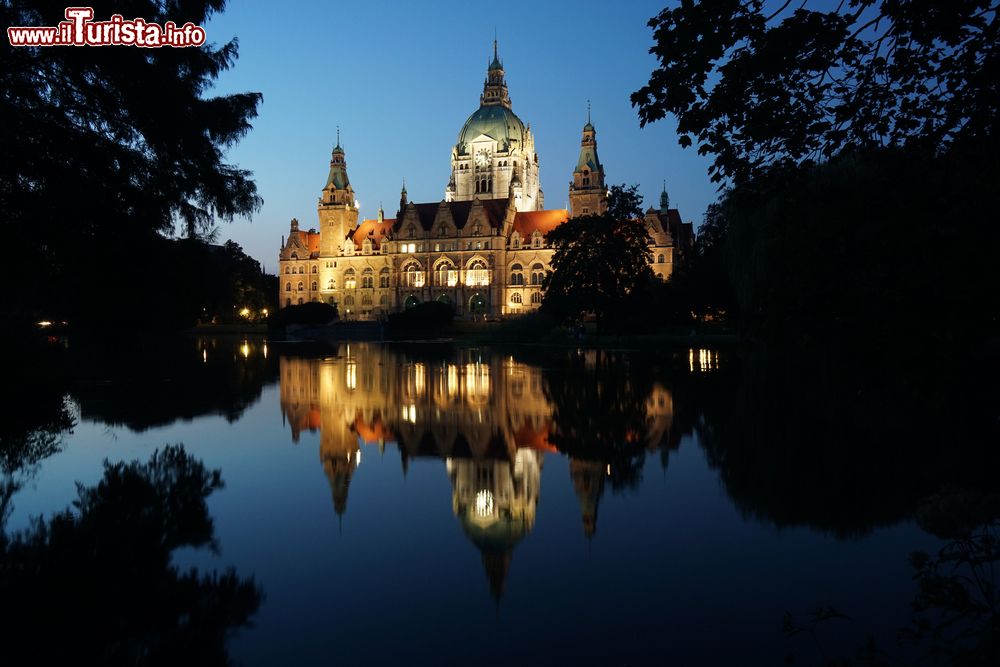 Immagine Il Neues Rathaus di Hannover (Germania) illuminato in una foto serale, dove si può apprezzare il riflesso sulle acque del laghetto Maschteich.