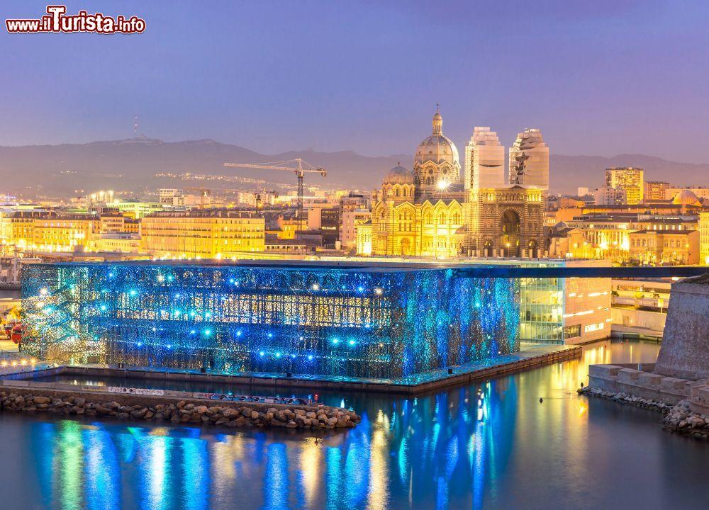 Immagine L'esterno del MuCEM illuminato alla sera e, sullo sfondo, la città di Marsiglia (Francia) - © vichie81 / Shutterstock.com