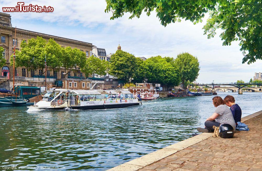 Immagine Ragazzi seduti sulla riva della Senna presso l'Île de la Cité osservano il viavai delle imbarcazioni turistiche che propongono tour acquatici di Parigi - foto © anyaivanova / Shutterstock.com