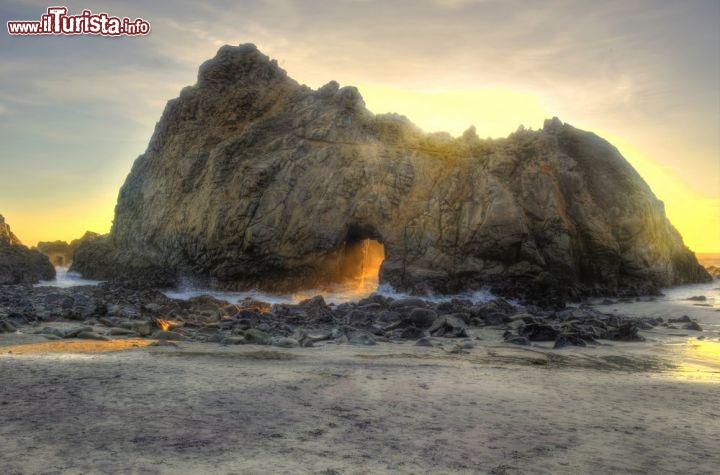 Keyhole Arch, Pfeiffer Beach, California - Ci troviamo sulla costa della California , il quel tratto di litorale selvaggio chiamato Big Sur. Qui sulla Pfeiffer Beach ammirate il Keyhole Arch, una singolare erosione naturale a forma di “buco della serratura”, che poco prima della fine all'anno si trasforma, al tramonto, in uno spettacolo quasi mistico. Nei giorni intorno al solstizio d'inverno (22-23 dicembre) la luce del sole, che tramonta sull'oceano, attraversa l'arco con una angolazione perfetta, e per circa 5 minuti le rocce assumono una colorazione arancione! Inutile dire che in quei giorni i fotografi si contendono la posizione migliore sulla spiaggia, che corrisponde ad un angolo di circa 35° alla destra dell'arco.  Pfeiffer Beach si trova a 34 miglia a sud di Monterey, all'interno del Pfeiffer State Park, e si raggiunge percorrendo la Cabrillo Highway (CA-1) e svoltando a destra sulla Sycamore Canyon Road. - © worldswildlifewonders / Shutterstock.com